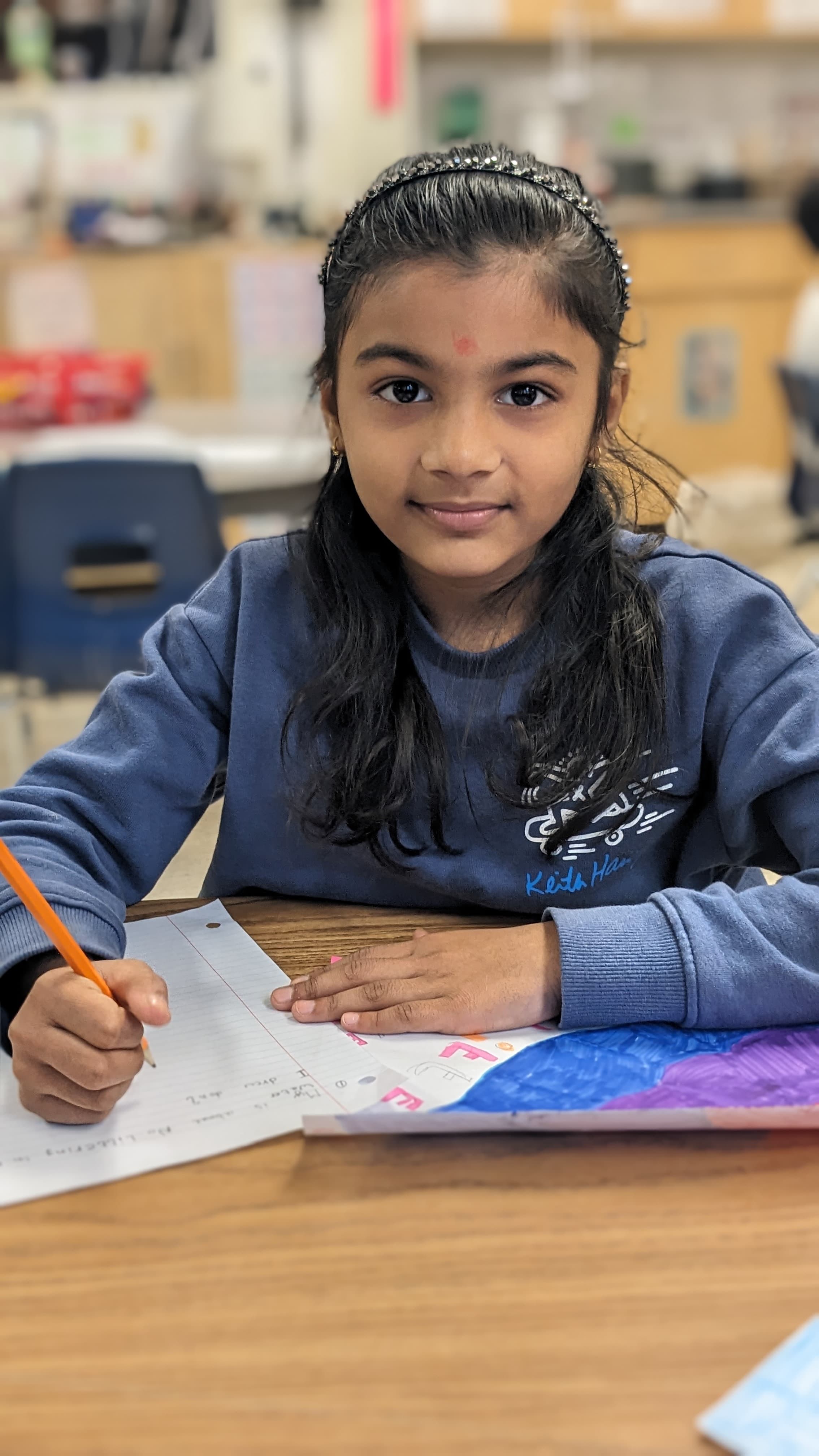 Photo of a LiftED program participant writing on a piece of paper and smiling at the camera